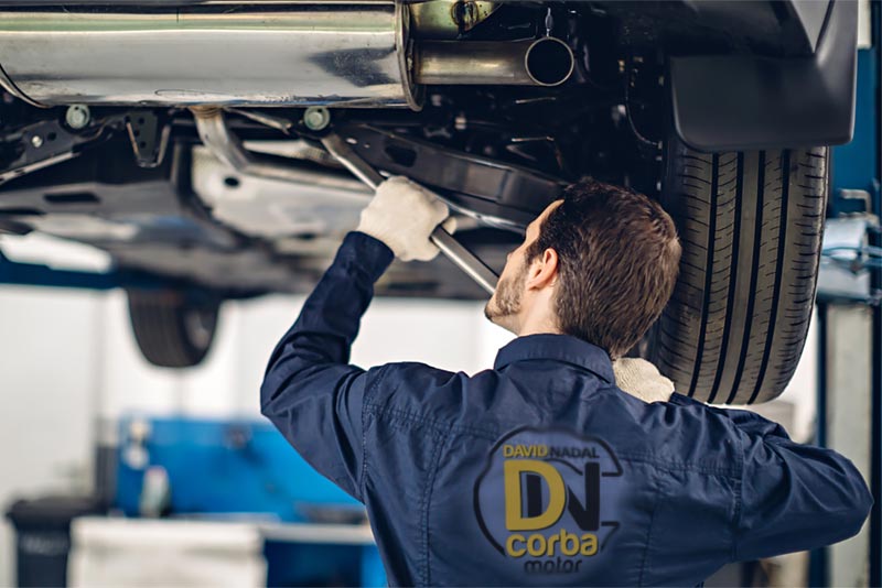 Mecánico de vehículos reparando un coche en un taller.